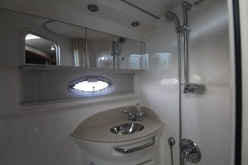 The image shows a sleek boat bathroom with a sink, mirror, and shower.