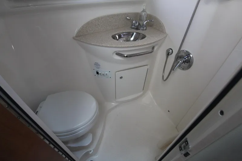 Bathroom with toilet, sink, and shower in a boat.