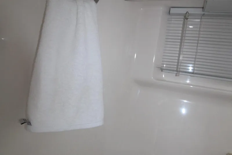 A bathroom with a white towel and a window with blinds.