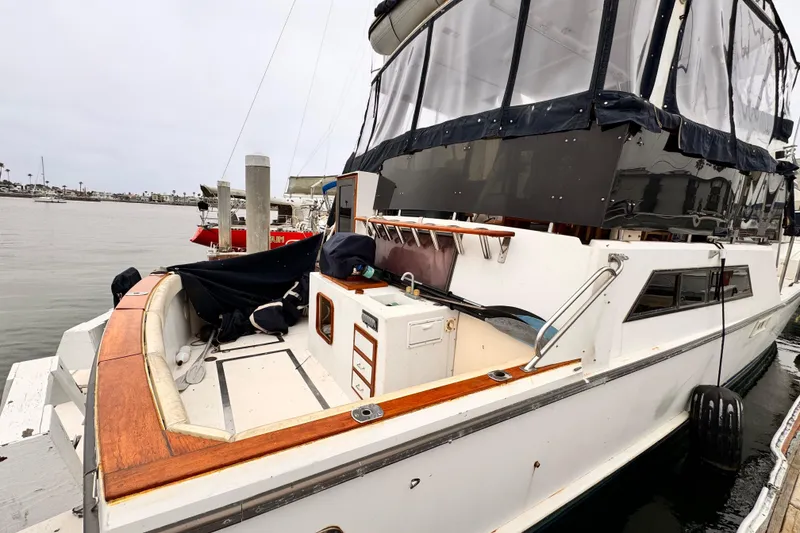 1985 Symbol 51 yacht docked, featuring a spacious deck and covered cabin area.