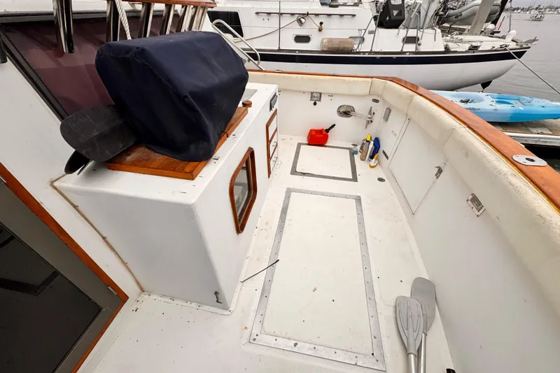 1985 Symbol 51 boat deck with storage, paddles, and cleaning supplies at marina.