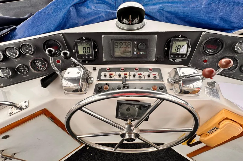 Boat control panel with steering wheel, gauges, and levers on a 1985 Symbol 51 model.