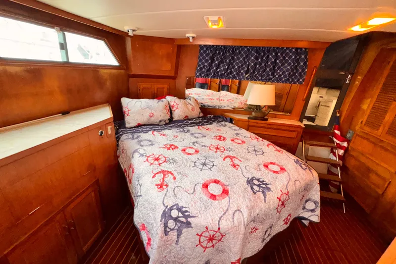 Cozy 1985 Symbol 51 yacht bedroom with nautical-themed bedding and wooden interior.