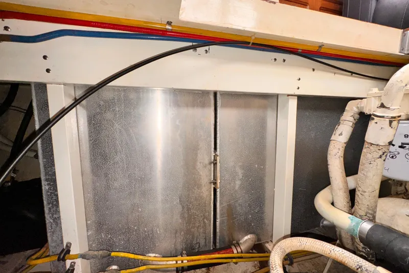 Engine room of a 1985 Symbol 51 yacht with visible pipes and wiring.
