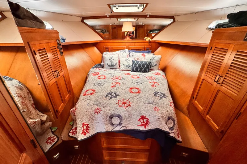 Cozy 1985 Symbol 51 yacht cabin with nautical-themed bedding and wooden cabinetry.