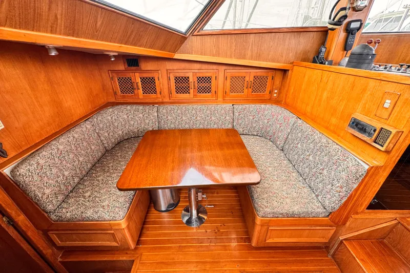 Cozy dining area in a 1985 Symbol 51 yacht with wooden table and cushioned seating.