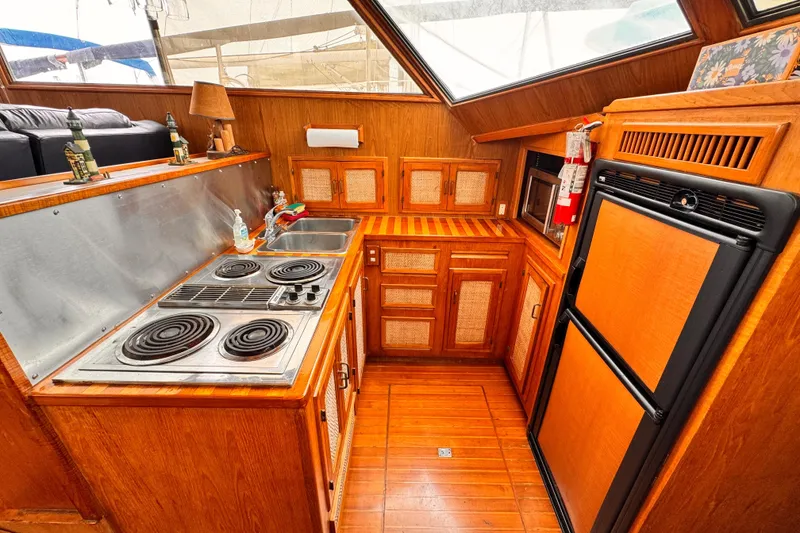 Vintage 1985 Symbol 51 yacht kitchen with wood cabinetry, stove, and refrigerator.