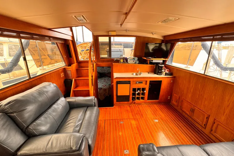 Luxurious 1985 Symbol 51 yacht interior with leather seating, wood paneling, and kitchenette.