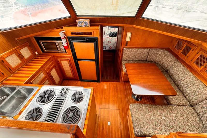 1985 Symbol 51 yacht interior with kitchen, dining area, and wooden cabinetry.