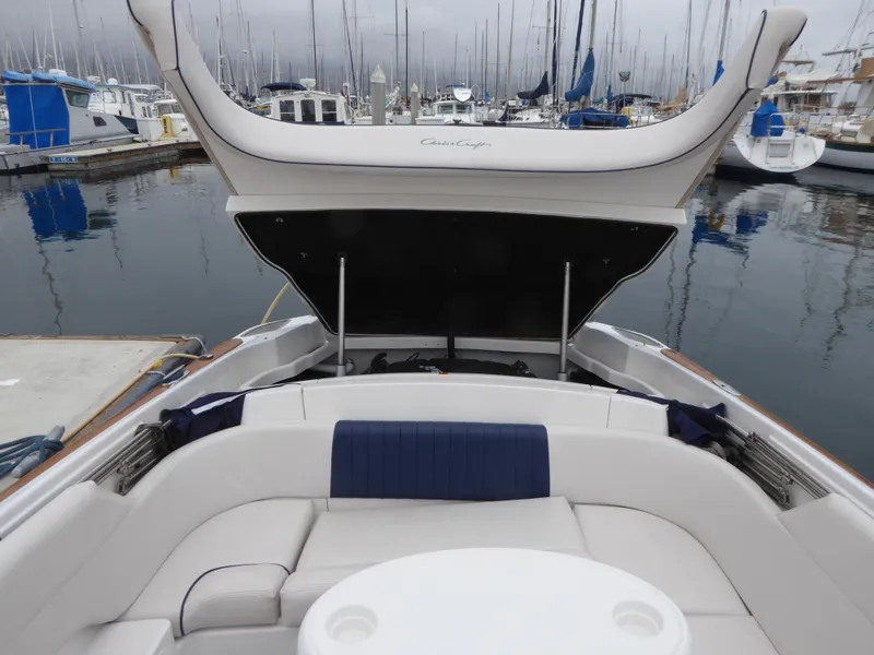 2004 Chris-Craft Corsair 25 boat in harbor with open storage compartment.