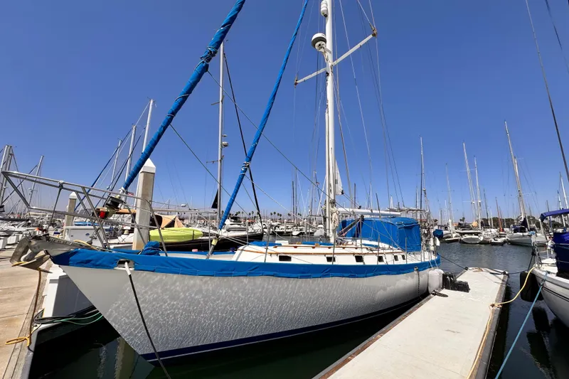 1982 Kelly Peterson 46 sailboat docked in a marina under clear blue skies.