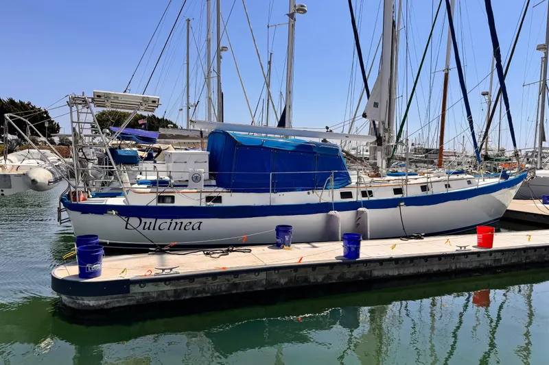 1982 Kelly Peterson 46 sailboat "Dulcinea" docked in a marina, surrounded by other boats.