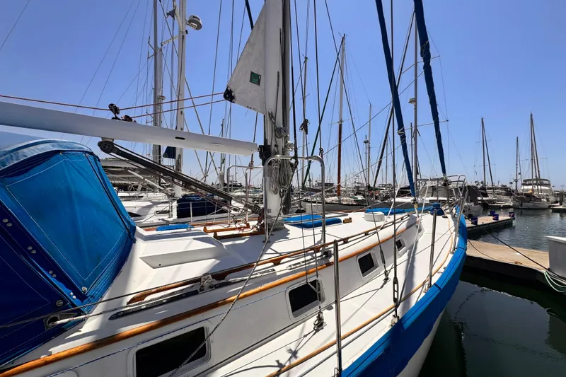1982 Kelly Peterson 46 sailboat docked in marina under clear blue sky.