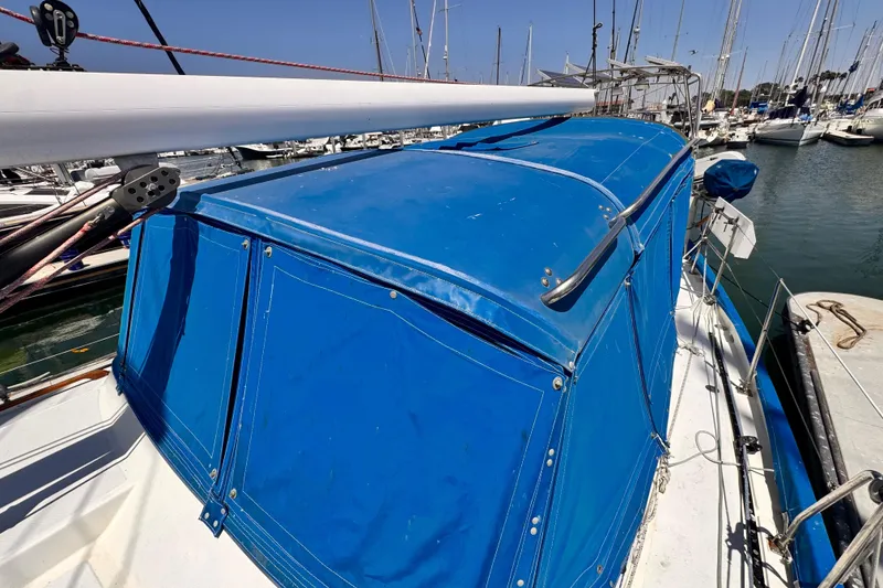 1982 Kelly Peterson 46 sailboat with blue canvas cover docked in marina.