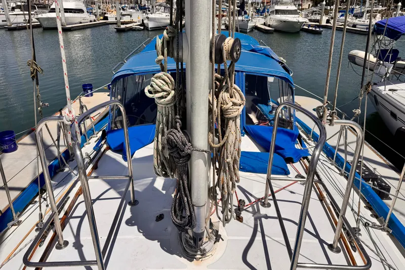 Deck view of 1982 Kelly Peterson 46 sailboat in marina, featuring ropes and blue canopy.