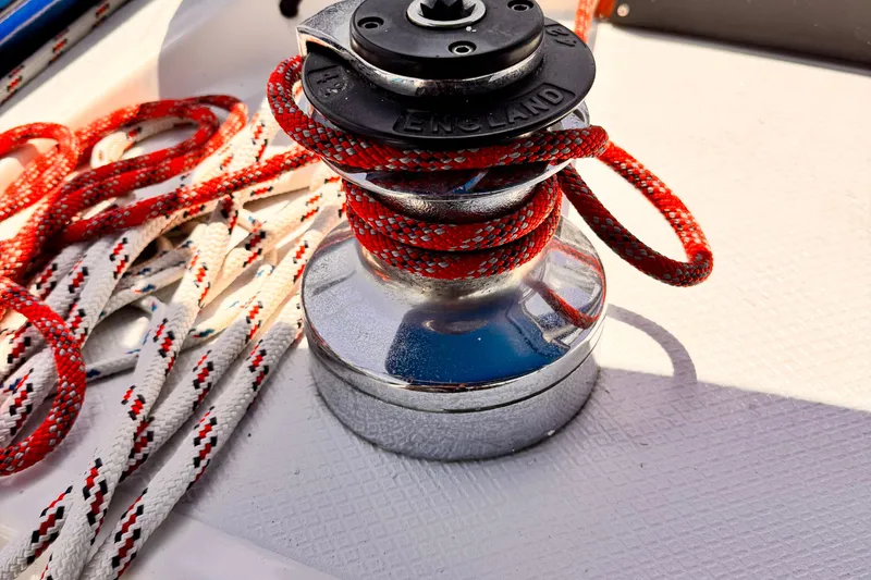 Winch with red and white ropes on 1982 Kelly Peterson 46 sailboat deck.