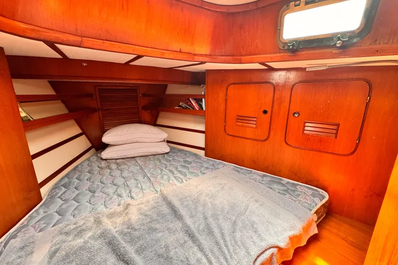 Cozy cabin interior of 1982 Kelly Peterson 46 sailboat with wooden finish and bedding.