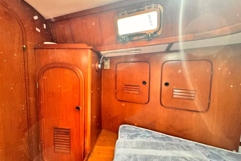 Cozy wooden cabin interior of 1982 Kelly Peterson 46 sailboat, featuring storage and bedding.