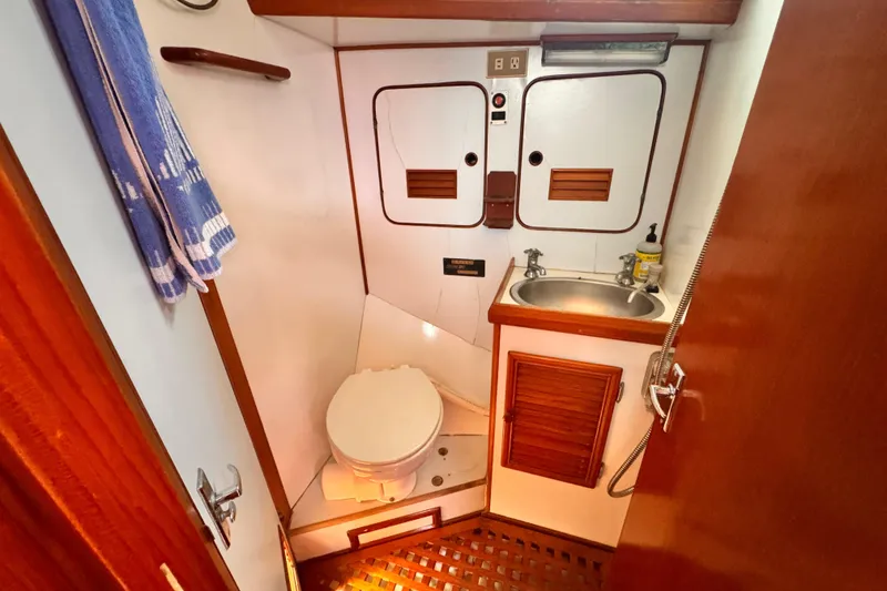 1982 Kelly Peterson 46 yacht bathroom with toilet, sink, and wooden accents.