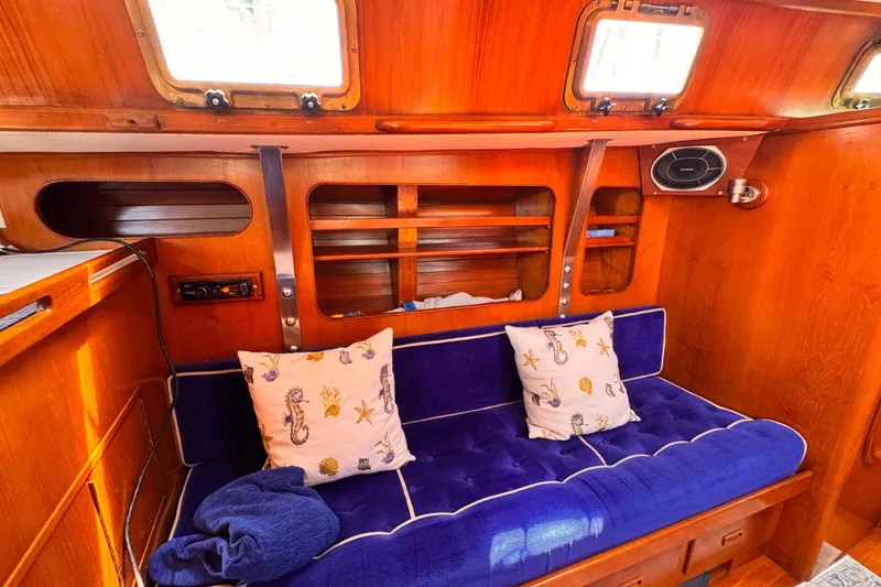 Interior of 1982 Kelly Peterson 46 yacht with blue cushioned seating and nautical-themed pillows.