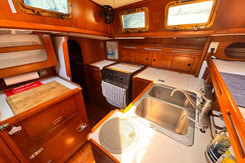1982 Kelly Peterson 46 yacht interior kitchen with wooden cabinetry and dual sinks.