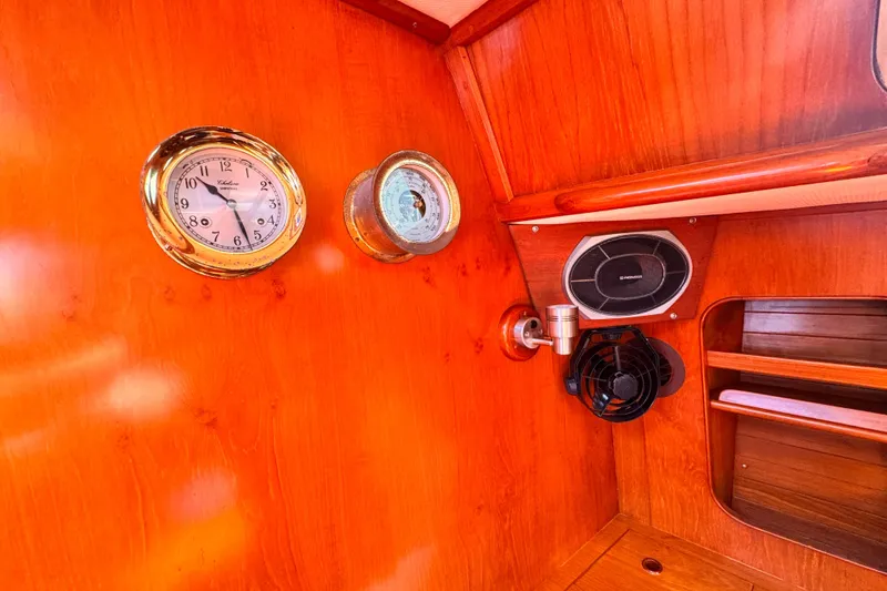 Interior of 1982 Kelly Peterson 46 yacht with clock, barometer, and speaker on wooden panel.