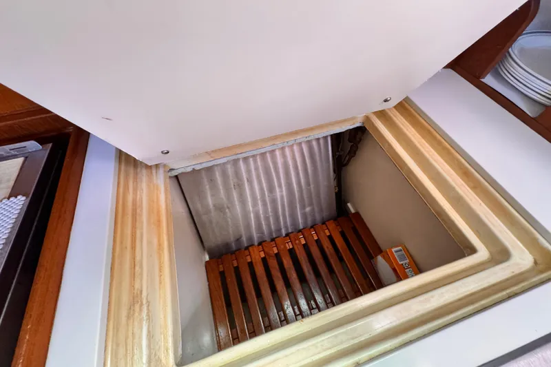 Open storage compartment on 1982 Kelly Peterson 46 yacht, featuring wooden slats and a small box.