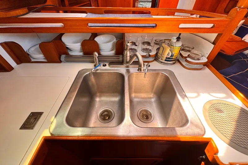 Galley sink area in 1982 Kelly Peterson 46 yacht, featuring dual basins and wooden cabinetry.