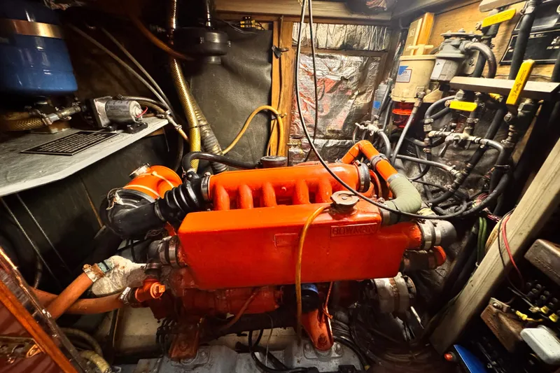 Engine room of 1982 Kelly Peterson 46 sailboat with red engine components.