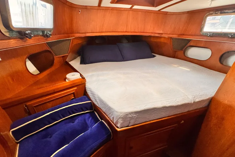 Cozy cabin interior of 1982 Kelly Peterson 46 sailboat with wooden finish and comfortable bedding.