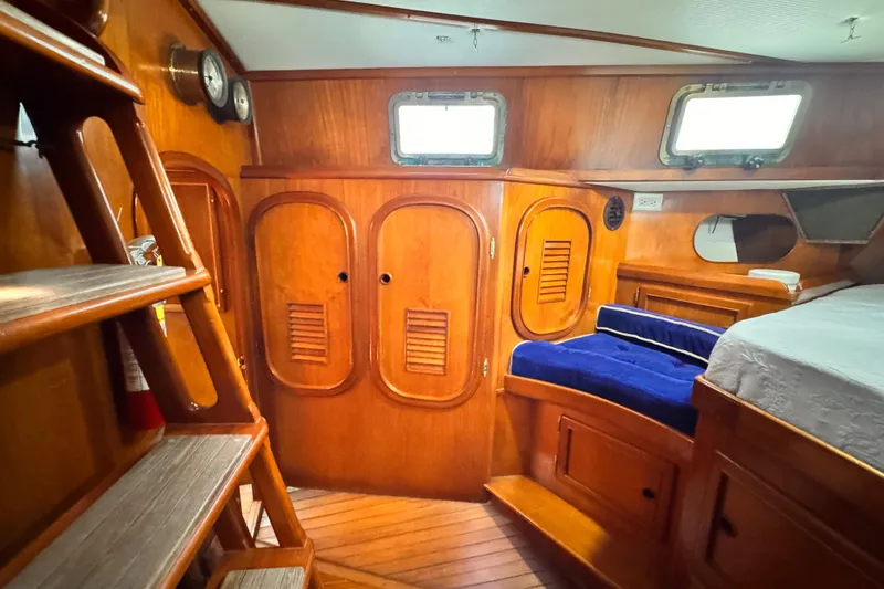 Interior of 1982 Kelly Peterson 46 sailboat with wooden cabinetry and blue seating.