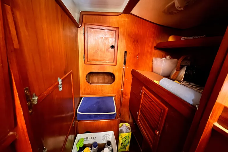 Interior of 1982 Kelly Peterson 46 sailboat with wooden cabinetry and storage shelves.