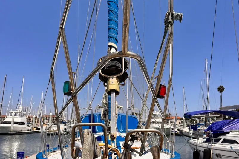 Sailboat rigging on a 1982 Kelly Peterson 46 in a marina, clear blue sky.