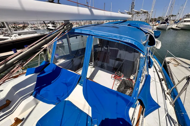 1982 Kelly Peterson 46 sailboat with blue canopy docked in marina.