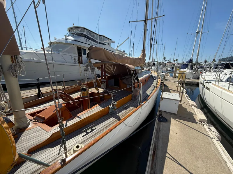 Historic 1932 Fellows & Stewart Yawl docked at marina, showcasing classic wooden design.