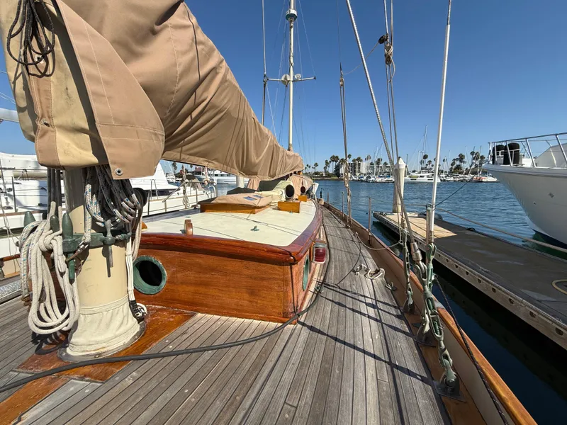 Historic 1932 Fellows & Stewart Yawl with wooden deck, docked in a sunny marina.