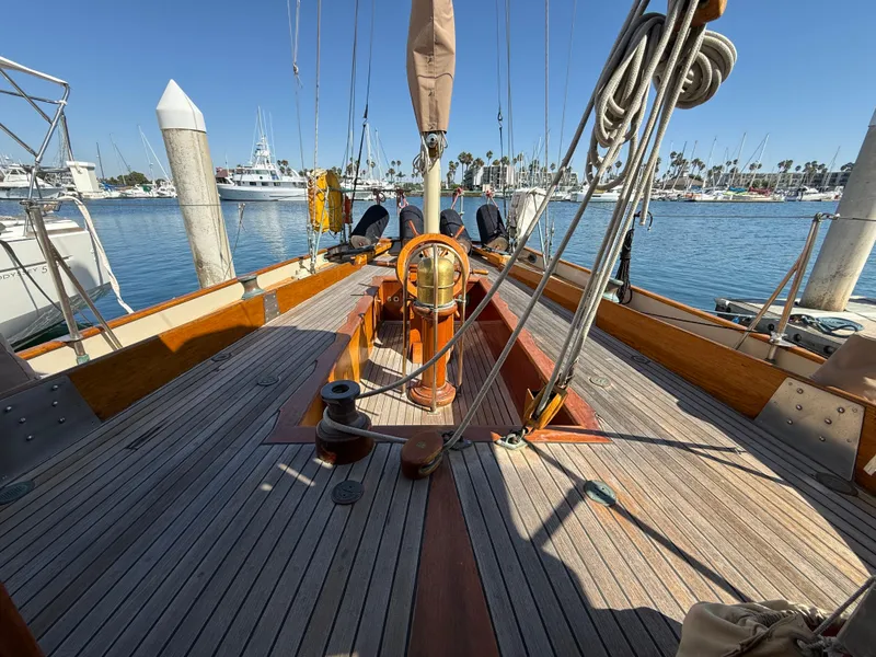 Historic 1932 Fellows & Stewart Yawl with wooden deck, docked in a sunny marina.