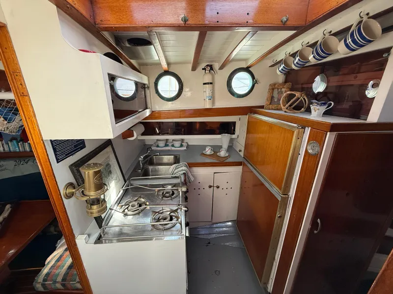 Interior of a 1932 Historic Fellows & Stewart Yawl, featuring a classic wooden galley kitchen.