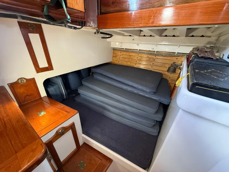 Interior of 1932 Historic Fellows & Stewart Yawl with stacked cushions and wooden cabinetry.