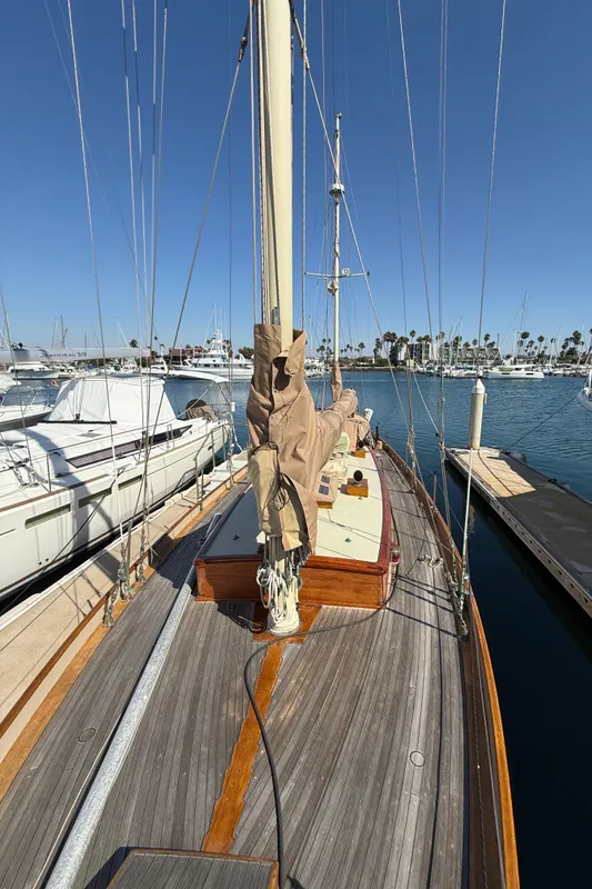 Historic 1932 Fellows & Stewart Yawl docked at marina under clear blue sky.