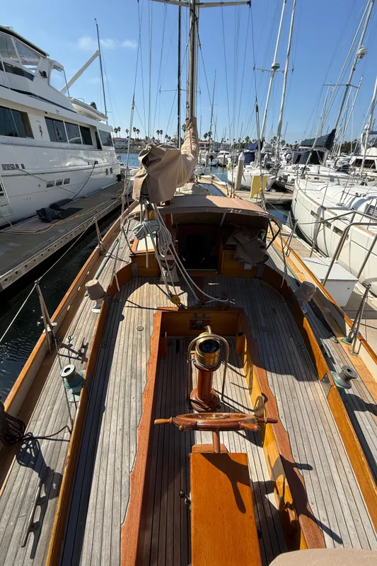 Historic 1932 Fellows & Stewart Yawl docked at marina, showcasing classic wooden deck design.