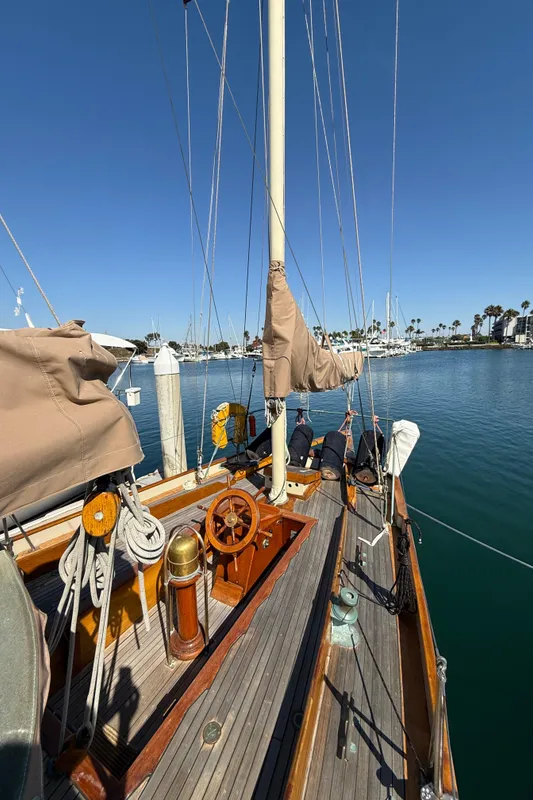 Historic 1932 Fellows & Stewart Yawl docked, showcasing wooden deck and rigging under clear blue sky.