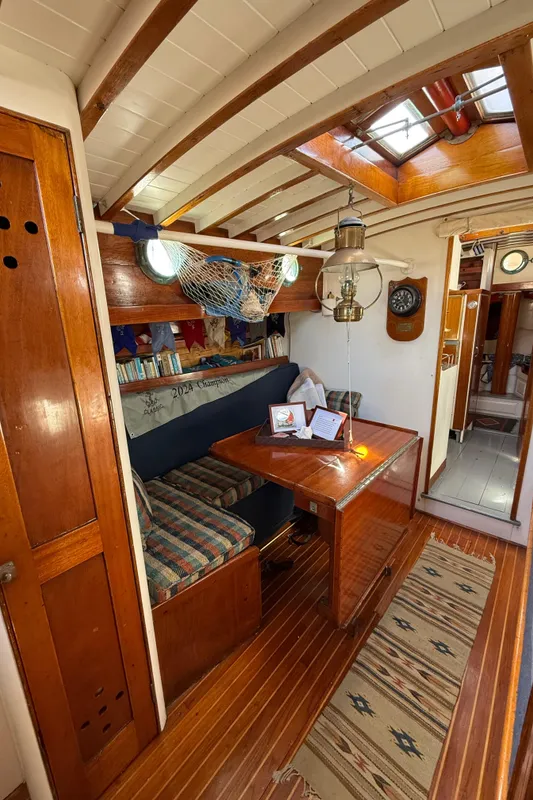 Interior of 1932 Historic Fellows & Stewart Yawl, featuring wooden furnishings and nautical decor.