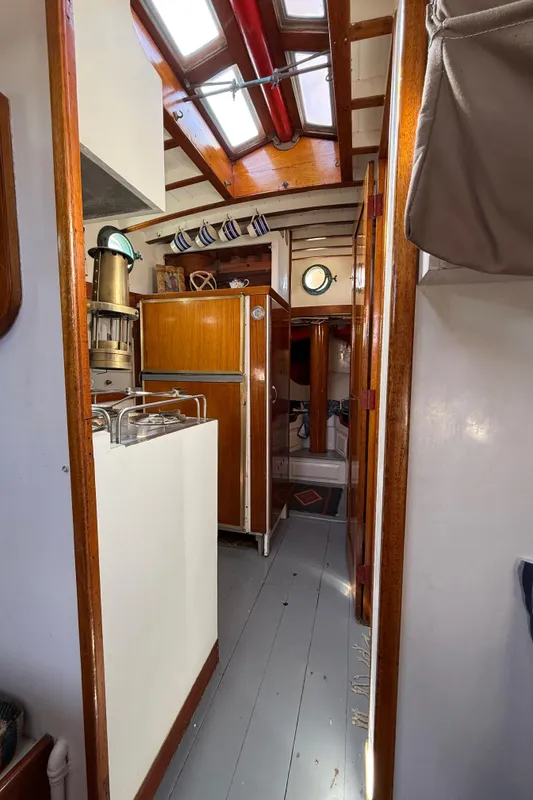 Interior of 1932 Fellows & Stewart Yawl, featuring wooden cabinetry and skylights.