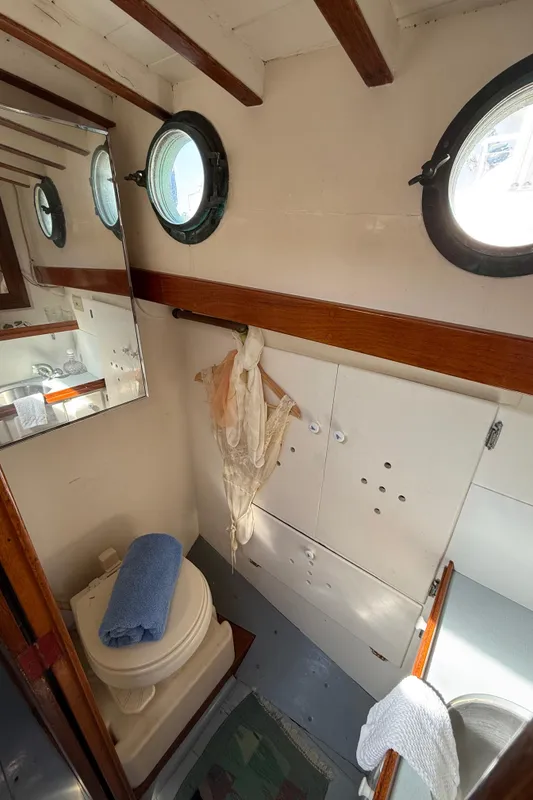 Interior of 1932 Fellows & Stewart Yawl with portholes, toilet, and wooden accents.