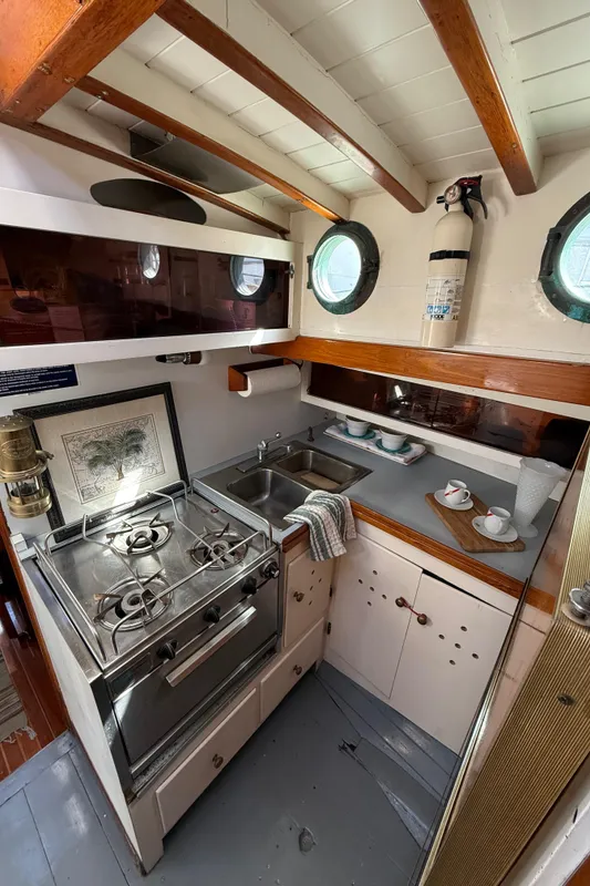 Interior of 1932 Historic Fellows & Stewart Yawl, featuring a compact kitchen with stove and sink.