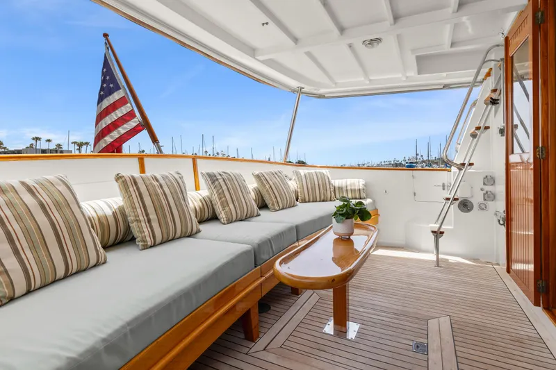 Kadey-Krogen 48 Whaleback 1996 yacht deck with cushioned seating and American flag.