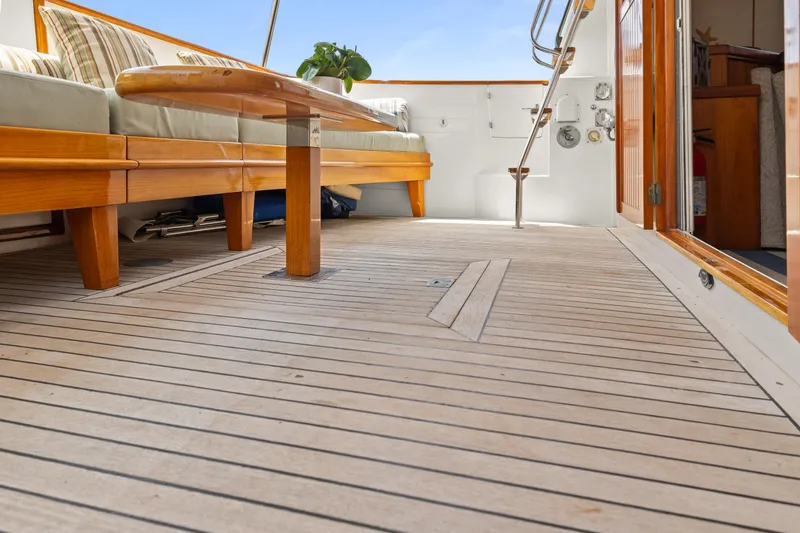 Kadey-Krogen 48 Whaleback 1996 yacht deck with wooden seating and open cabin door.