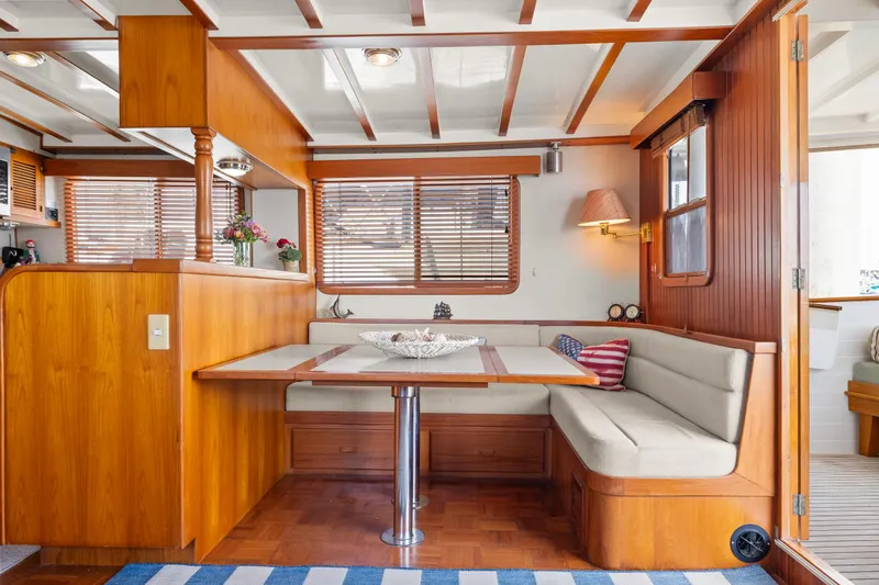 Interior of 1996 Kadey-Krogen 48 Whaleback yacht with wooden dining area and cozy seating.