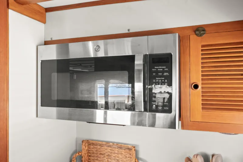 Microwave in 1996 Kadey-Krogen 48 Whaleback yacht kitchen, with wooden cabinetry.